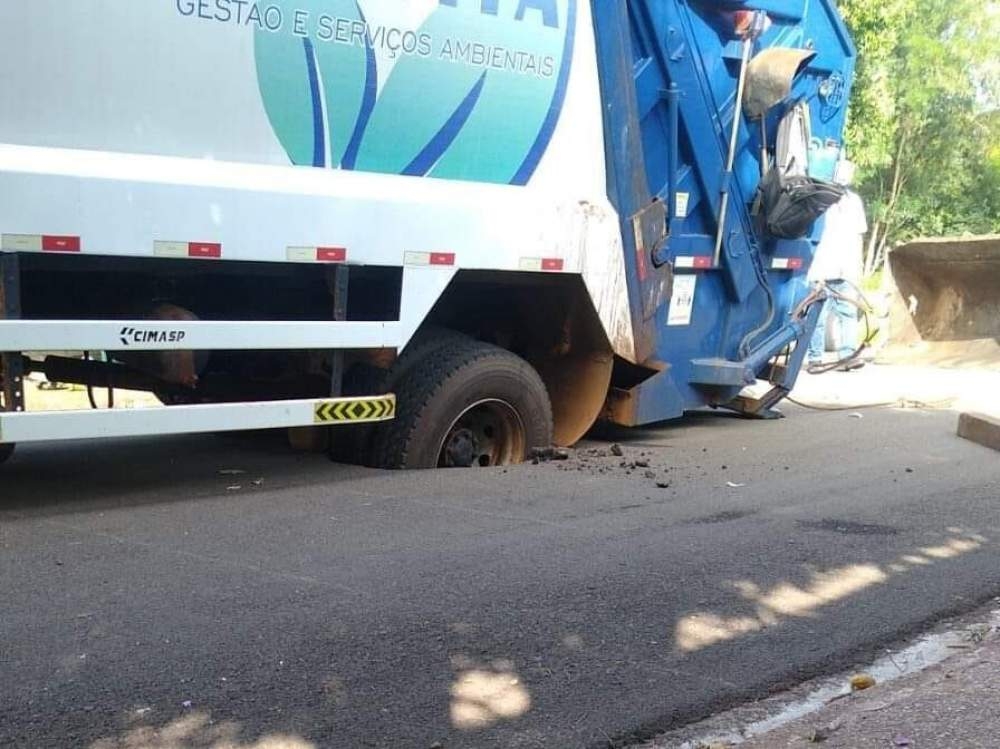 Caminhão da coleta de lixo fica preso em cratera no asfalto na Cohab do Pereira Jordão em Andradina