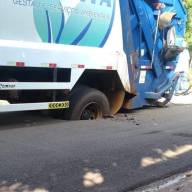 Caminhão da coleta de lixo fica preso em cratera no asfalto na Cohab do Pereira Jordão em Andradina